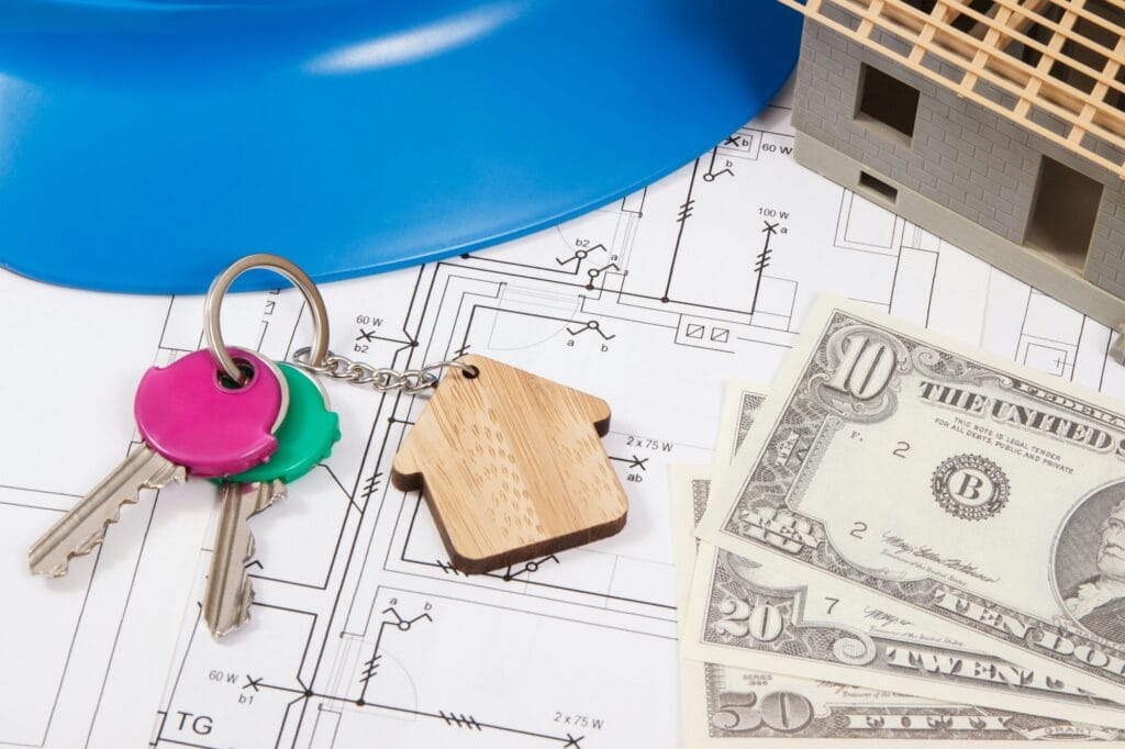 Home keys, currencies dollar, electrical construction diagrams and small house under contruction